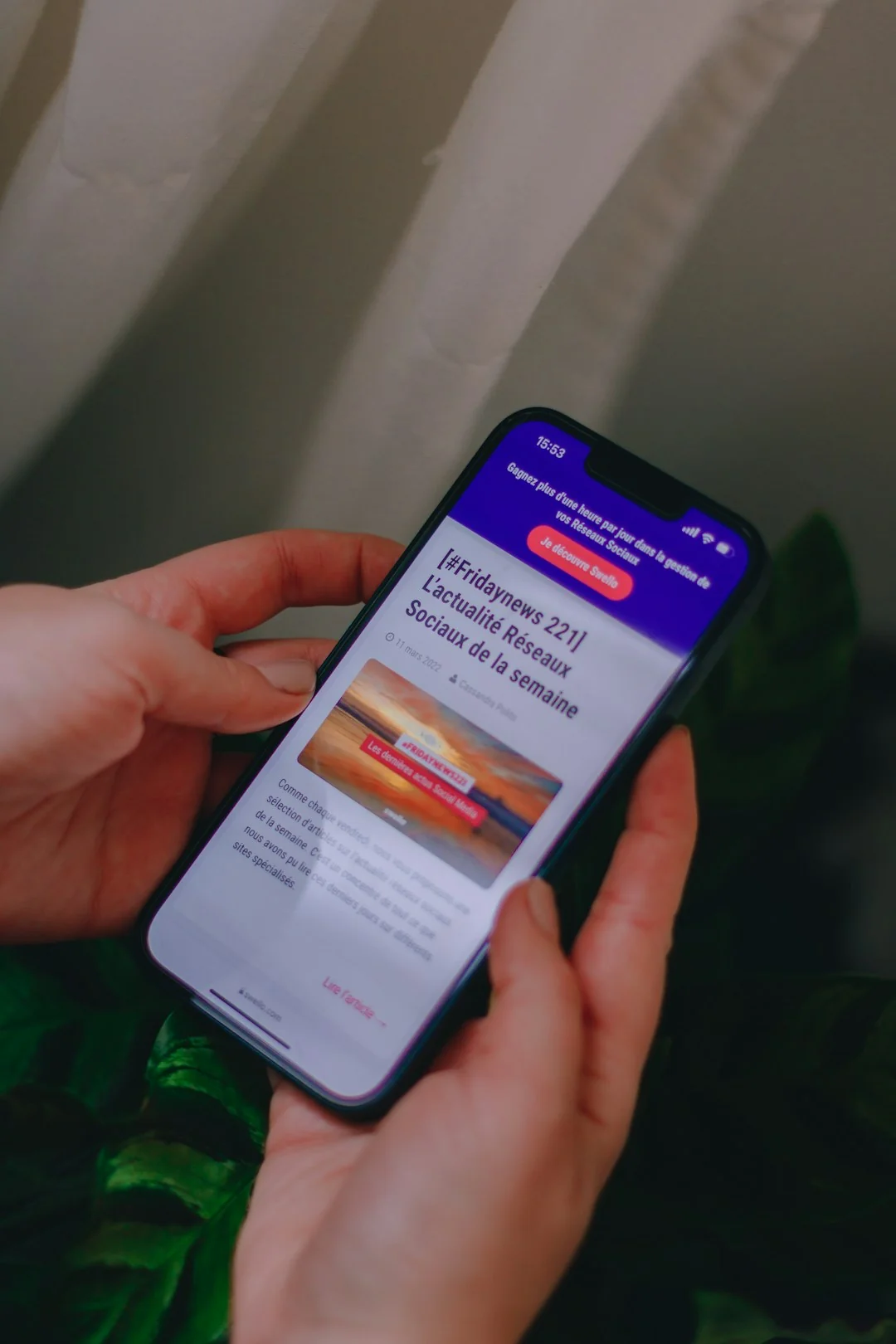 Des mains tapent sur un ordinateur portable tout en tenant un smartphone, illustrant un environnement de travail multitâche.